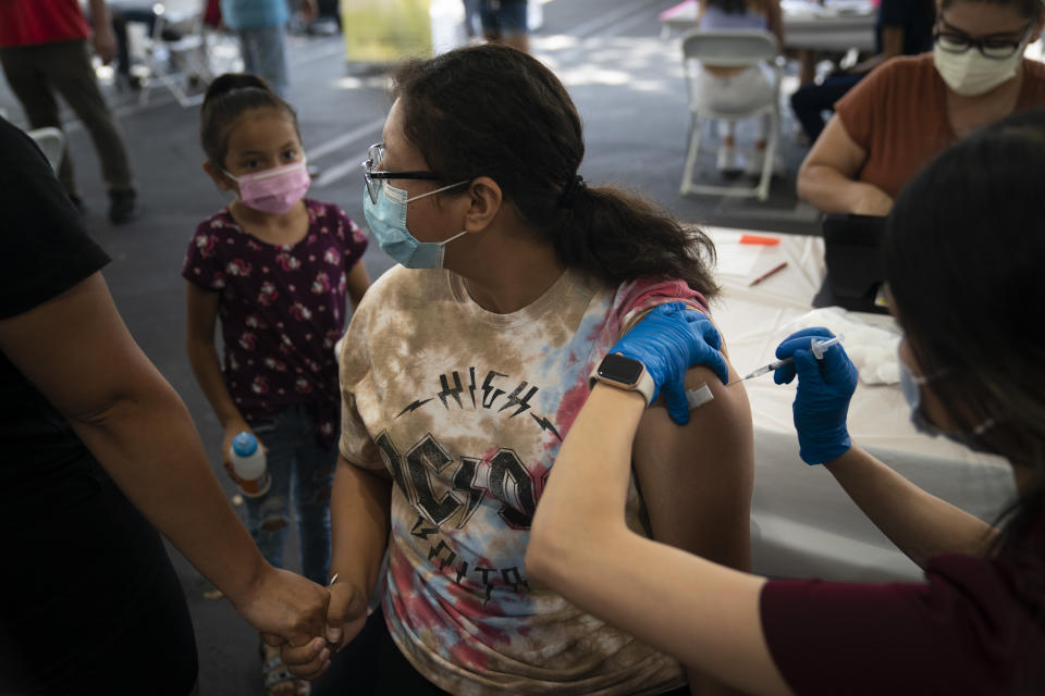 FILE - Holding her mother's hand, Brianna Vivar, 14, looks away while receiving the Pfizer COVID-19 vaccine from pharmacy technician Mary Tran at a vaccine clinic set up in the parking lot of CalOptima, Saturday, Aug. 28, 2021, in Orange, Calif. The U.S. death toll from COVID-19 has hit 1 million, less than 2 1/2 years into the outbreak. (AP Photo/Jae C. Hong, File)
