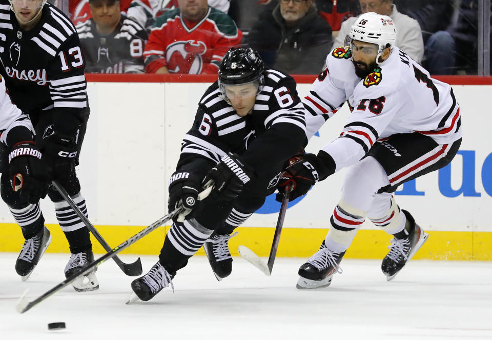 New Jersey Devils defenseman John Marino (6) reaches for the puck as Chicago Blackhawks left wing Jujhar Khaira (16) defends during the second period of an NHL hockey game Tuesday, Dec. 6, 2022, in Newark, N.J. (AP Photo/Noah K. Murray)