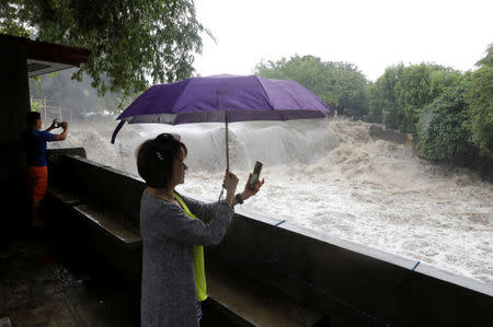 Residents use their mobile phones to take footage of rampaging floodwaters in Las Pinas, Metro Manila as a storm sweeps across the main Luzon island, Philippines, September 12, 2017. REUTERS/Erik De Castro