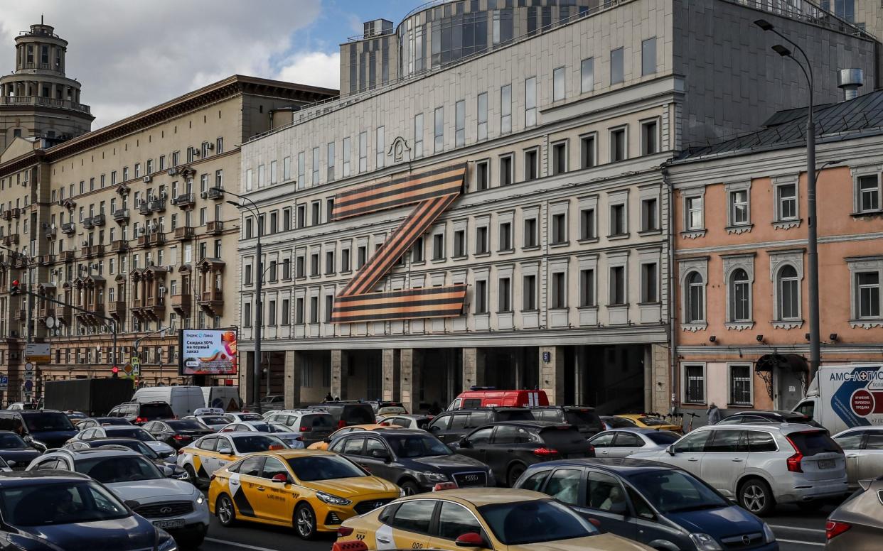 Cars stuck in traffic in front of a theatre building decorated with the letter Z in Moscow, Russia, 30 March 2022. The letter Z has been used by Russian forces as an identifying sign on their vehicles in Ukraine. - Shutterstock