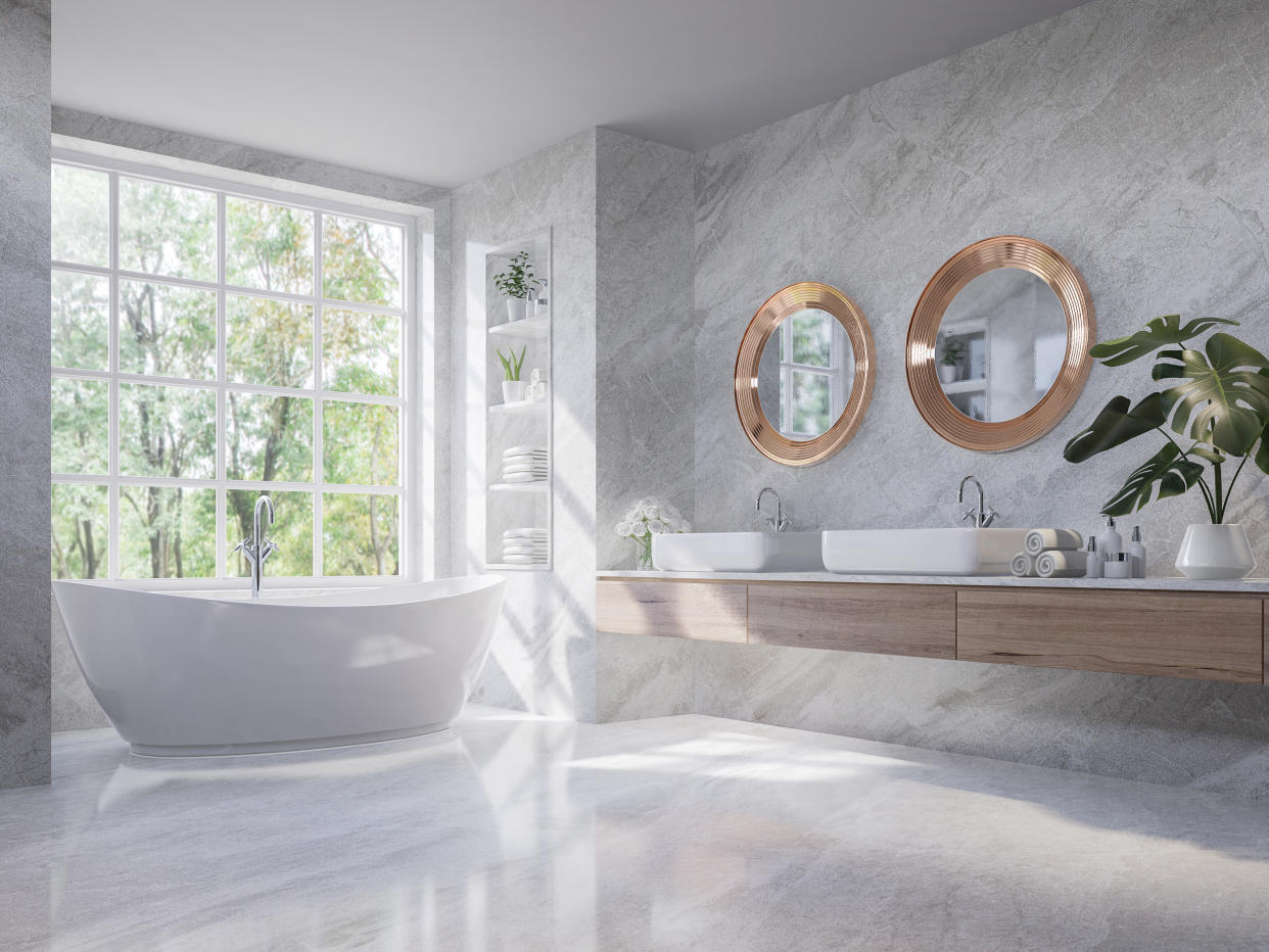 Home renovation:  Luxury style light gray bathroom 3d render,There are marble floor and wall ,wooden sink counter and copper frame mirror,Rooms have large windows, overlook nature view,sunlight shining into the room.