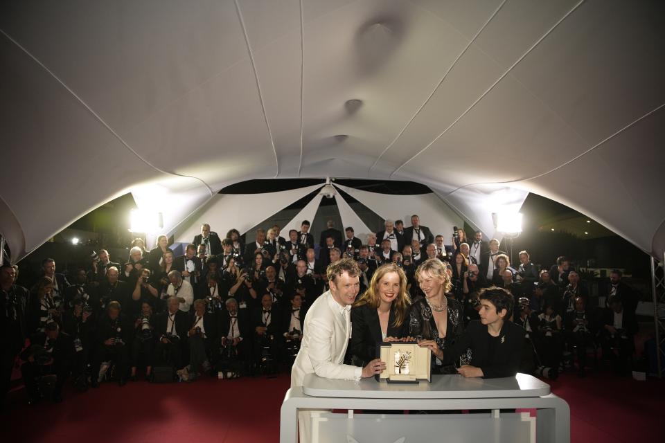 Justine Triet, winner of the Palme d'Or for 'Anatomy of a Fall,' second from left, Antoine Reinartz, from left, Sandra Huller and Milo Machado Graner pose for photographers during a photo call following the awards ceremony at the 76th international film festival, Cannes, southern France, Saturday, May 27, 2023. (AP Photo/Daniel Cole)