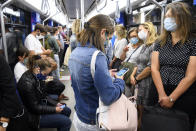 People wearing protective mask ride the "Transports publics lausannois", TL, Metro M2 (underground) during the coronavirus disease (COVID-19) outbreak, in Lausanne, Switzerland, Monday, July 6, 2020. In Switzerland, from Monday 6 July, people aged 12 and over must wear a mask in all public transport, trains, trams and buses, as well as in cable cars and boats. (Laurent Gillieron/Keystone via AP)
