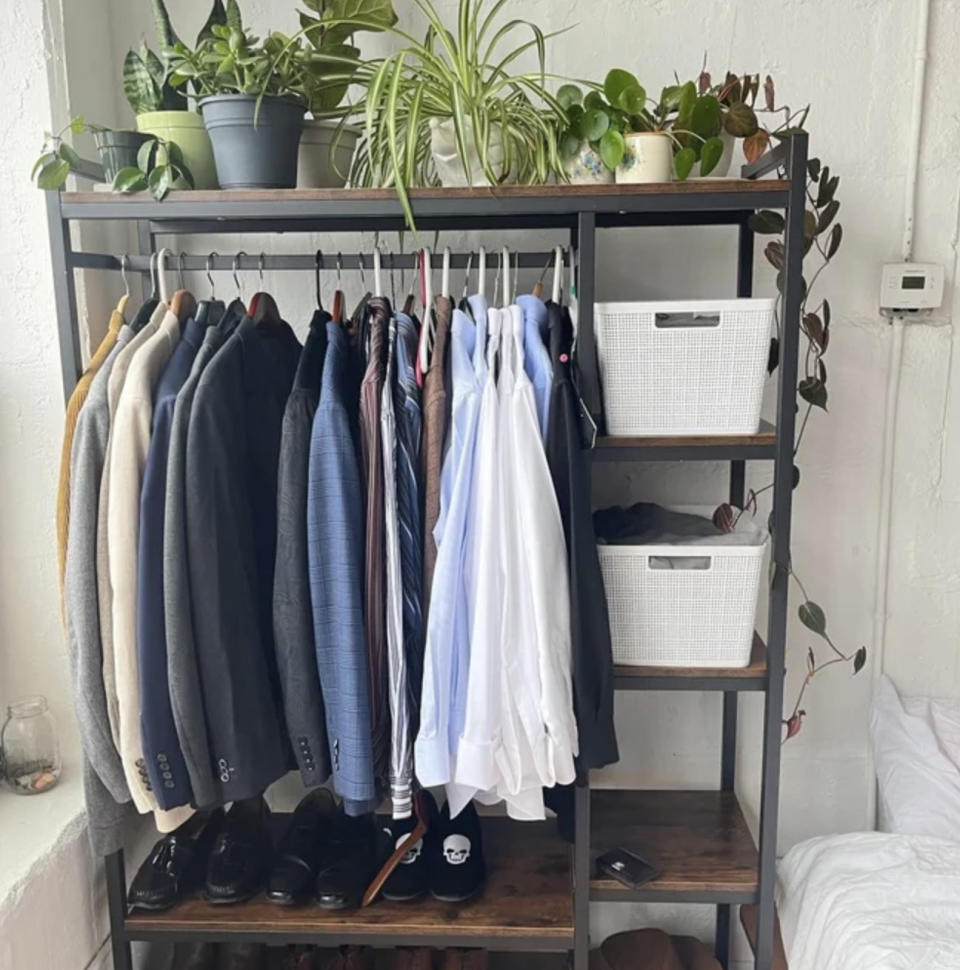a standalone closet with shirts, shoes, bins, and plants