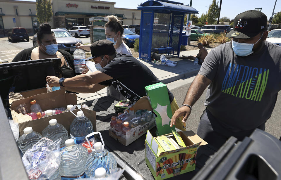 FILE - A group of community members, from left, Suzana Perez, Maricella Perez, Gavino Vasquez and Francisco Ramos hand out water, ice, popsicles and Gatorade to individuals experiencing homelessness, during a heat wave on Sept. 5, 2022, in Santa Rosa, Calif. Ten years ago scientists warned the world about how climate change would amplify extreme weather disasters. There are now deadly floods, oppressive heat waves, killer storms, devastating droughts and what scientists call unprecedented extremes as predicted in 2012. (Kent Porter/The Press Democrat via AP, File)
