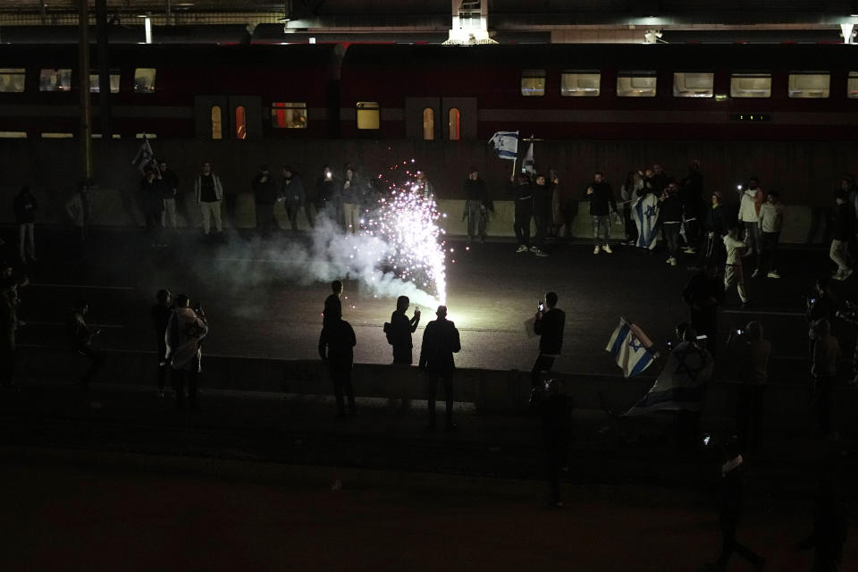 Right-wing Israelis light flares as they block a main road during a rally in support of plans by Prime Minister Benjamin Netanyahu's government to overhaul the judicial system, in Tel Aviv, Israel, Thursday, March 30, 2023. (AP Photo/Ariel Schalit)