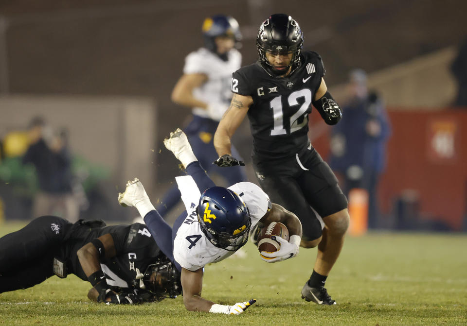 West Virginia running back Leddie Brown (4) is upended by Iowa State defensive back Arnold Azunna, left, as Iowa State defensive back Greg Eisworth (12) works to finish the tackle during the second half of an NCAA college football game, Saturday, Dec. 5, 2020, in Ames, Iowa. Iowa State won 42-6. (AP Photo/Matthew Putney)