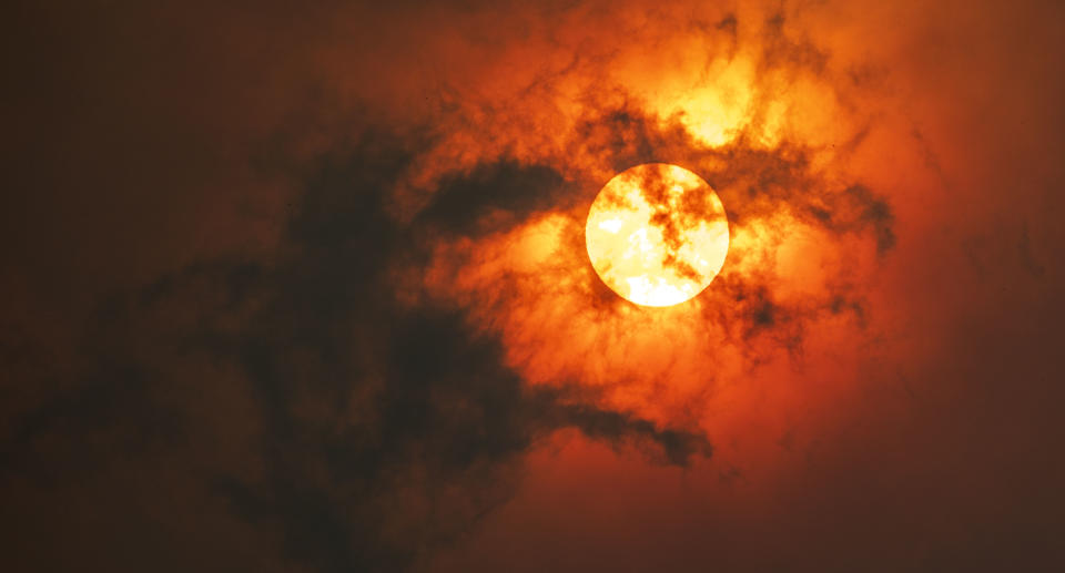 Sun through dark smoke clouds from bush fire with red glow, climate change in Australia. Source: Getty Images 