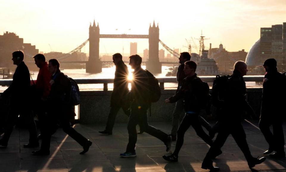 Morning commuters walk across London Bridge with Tower Bridge in the background