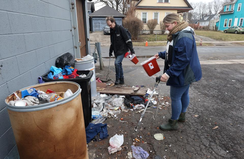 Shannon Pritzkau and Stephen Wallace collect discarded syringes from a parking lot in the North Clinton Ave. community.