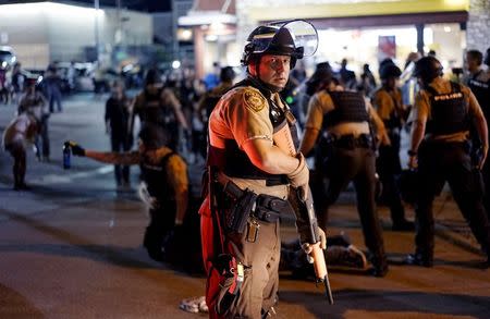 A police officer holds his weapon as a protester is detained (rear) in Ferguson, Missouri, August 10, 2015. REUTERS/Rick Wilking