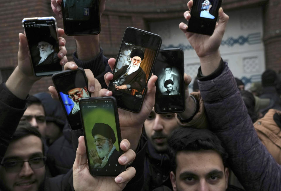 Iranian demonstrators show photos of the Supreme Leader Ayatollah Ali Khamenei on the screen of their cellphones during their protest against cartoons published by the French satirical magazine Charlie Hebdo that lampoon Iran's ruling clerics, in front of the French Embassy in Tehran, Iran, Wednesday, Jan. 11, 2023. (AP Photo/Vahid Salemi)