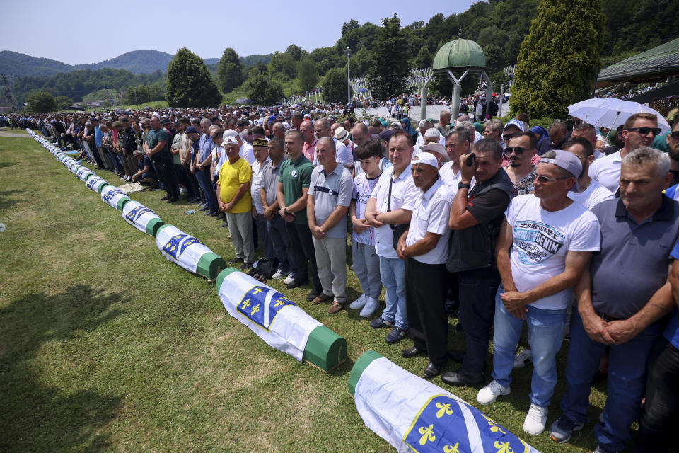 Bosnian muslim men pray next to the coffins containing the remains of 30 newly identified victims of the Srebrenica Genocide in Potocari, Bosnia, Tuesday, July 11, 2023. Thousands gather in the eastern Bosnian town of Srebrenica to commemorate the 28th anniversary on Monday of Europe's only acknowledged genocide since World War II. (AP Photo/Armin Durgut)