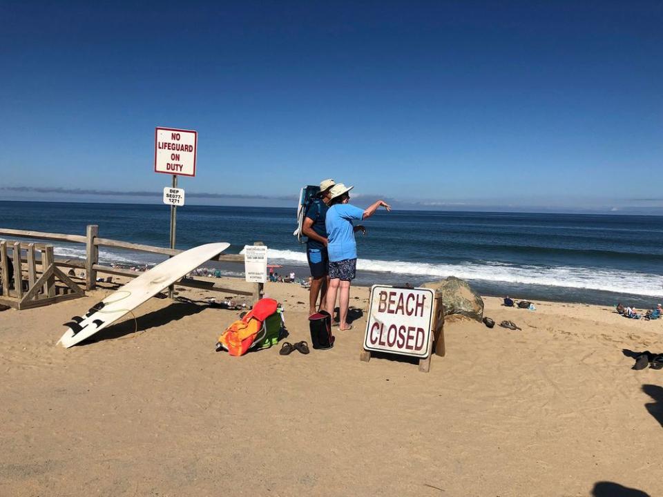 People stand on the beach after the shark attack