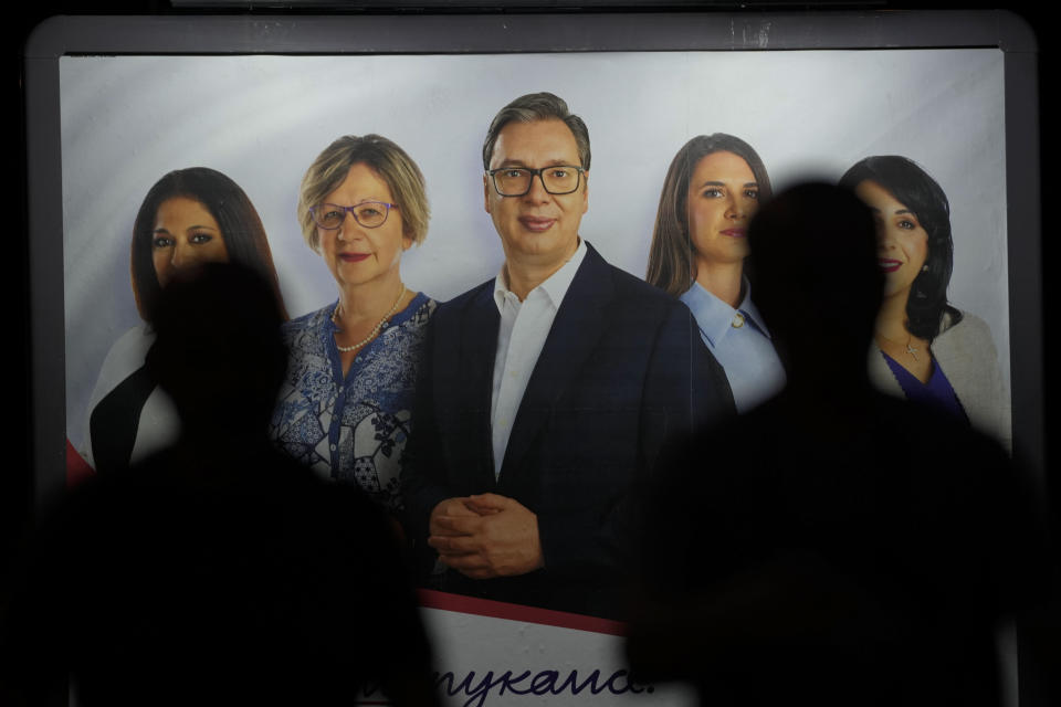 People walk in front of a pre-election billboard showing Serbian President Aleksandar Vucic, center, along with associates in Belgrade, Serbia, Wednesday, May 29, 2024, ahead of the municipal vote set for June 2. Voters in Serbia go to the polls this weekend in a municipal election for dozens of cities and towns, including a rerun vote in the capital Belgrade where ruling populists were accused of a fraud at a previous vote in December. The right-wing Serbian Progressive Party of President Aleksandar Vucic is seen as a favorite ahead of the Sunday balloting which could further secure the strongman's already vast hold on power. (AP Photo/Darko Vojinovic)