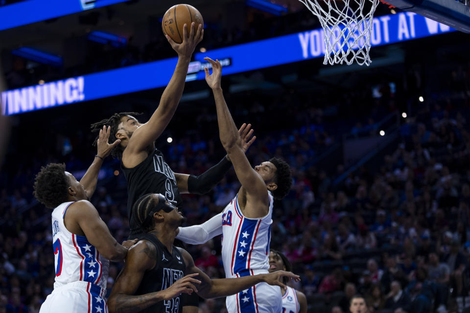 Brooklyn Nets' Trendon Watford, top center, goes up to shoot with Philadelphia 76ers' Kyle Lowry, left, and Tobias Harris, right, defending during the first half of an NBA basketball game, Sunday, April 14, 2024, in Philadelphia. (AP Photo/Chris Szagola)
