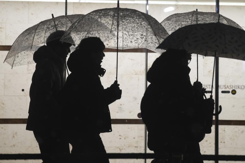 People are silhouetted as they use umbrellas to shelter from a snowfall, in Tokyo, Monday, Feb. 5, 2024. Japan Meteorological Agency warned more Metropolitan areas braced for snowfall Monday. (AP Photo/Eugene Hoshiko)