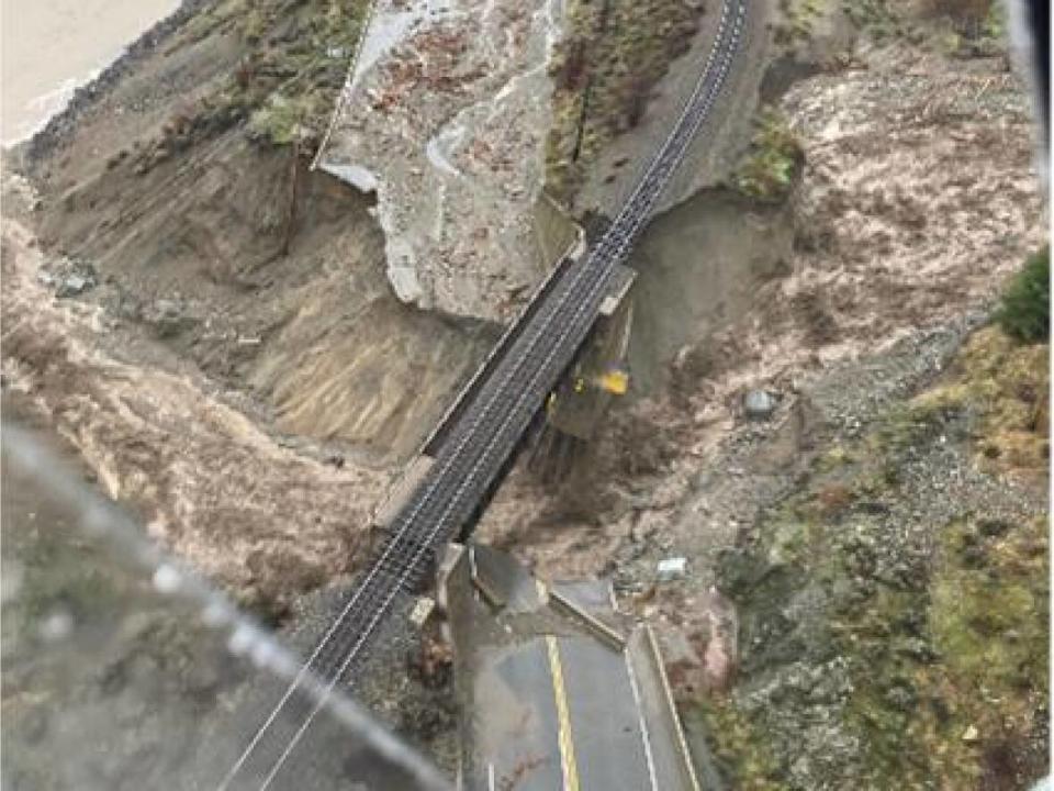 The collapsed section of Highway 1, spanned by a rail bridge, at Tank Hill, near Lytton, B.C., on Nov. 15. The surrounding hillsides had been scoured by wildfires earlier in the year. (B.C. Ministry of Transportation/Twitter - image credit)