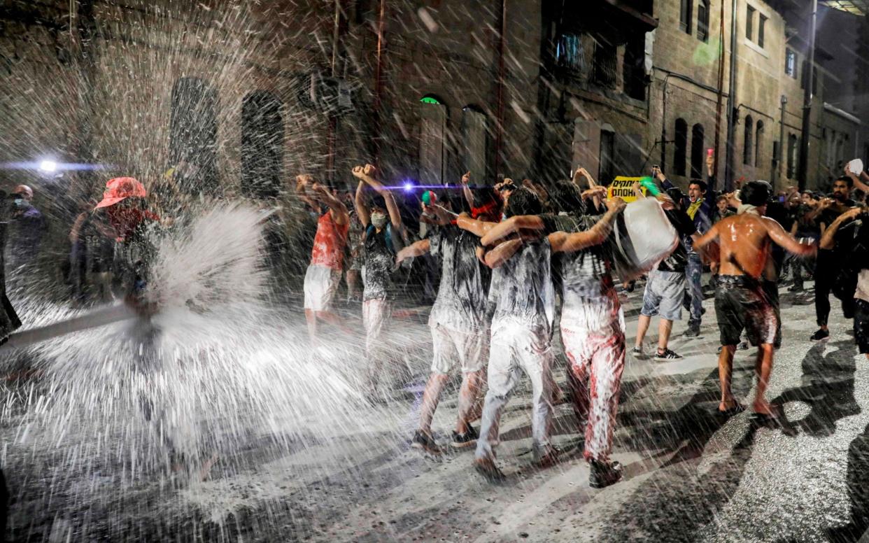 Israeli police spray protesters (clad in masks due to the COVID-19 coronavirus pandemic) with water cannon  - Ahmad Gharabli/AFP