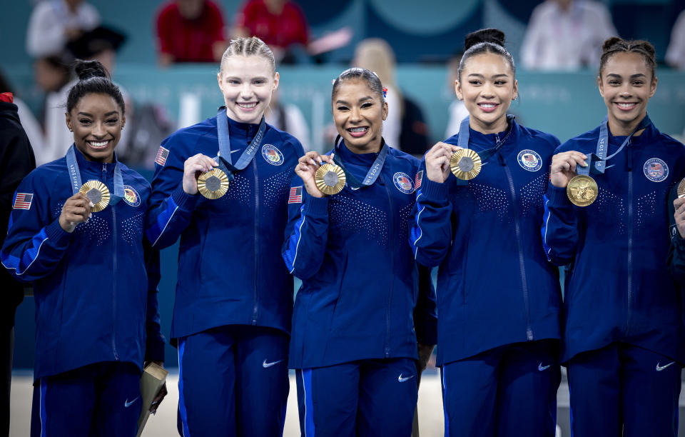 Team USA holding their Olympic gold medals: (from left to right) Simone Biles, Jade Carey, Jordan Chiles, Sunisa Lee and Hezly Rivera.