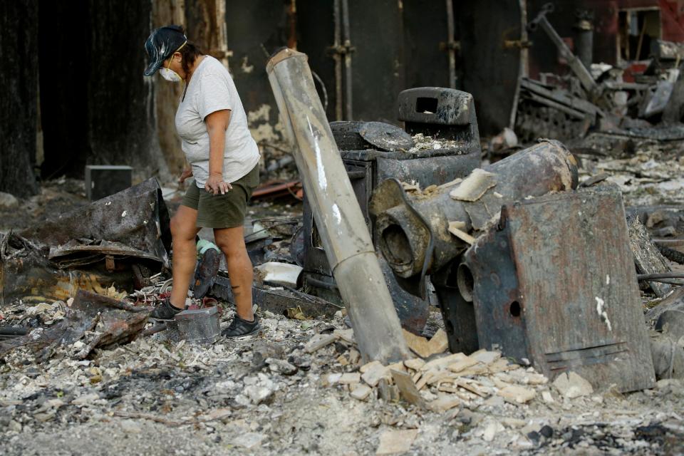 Bernadette Laos looks for salvageable items in her home destroyed by the Kincade Fire near Geyserville, Calif., on Oct. 31, 2019.