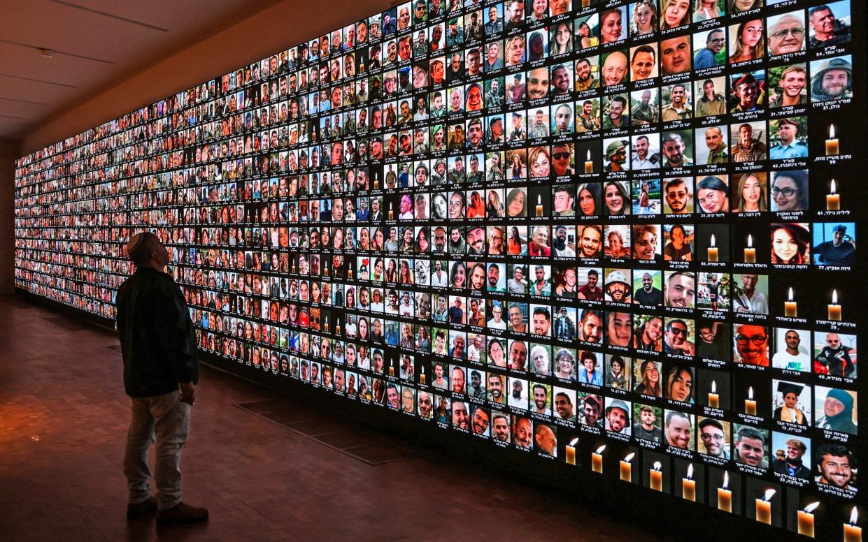 A visitor looks at a giant backlight screen bearing the portraits of Israelis who were killed during the October 7 attacks by Hamas