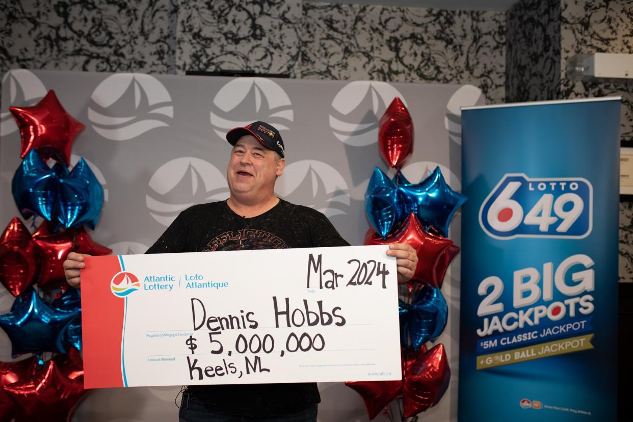 Man holds a $5 million lotto jackpot cheque. 