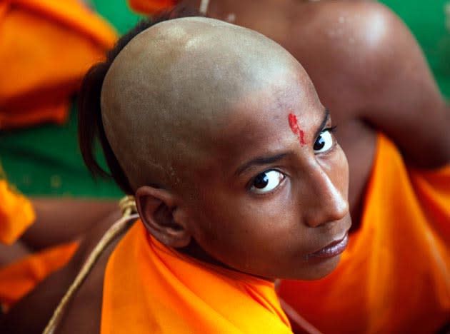 A Hindu boy looks on as he listens to the Guru, unseen, during the "janeu" rituals at the Magh Mela festival in Allahabad, India, Sunday, Feb. 6, 2011. Janeu is a holy thread that is worn by the Hindu Brahmins of India. This holy thread suggests the development of a male, from a young boy to a man. (AP Photo/Rajesh Kumar Singh)