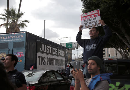 Protesters watch as members of the Teamsters Union participate in a tractor trailer caravan surrounding the LA Metro Detention Center in support of port truck drivers and others threatened by deportation if the courts or congress don't stop the termination of Temporary Protected Status (TPS) in Los Angeles, California, U.S. October 3, 2018. REUTERS/Kyle Grillot