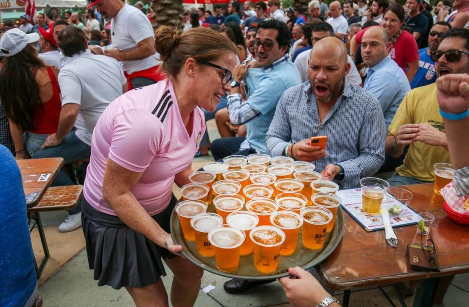 Una mesera llevando una bandeja con vasos llenos de cerveza a una mesa mientras los fans ven el partido entre Estados Unidos e Irán, durante una fiesta para ver el Mundial en Fritz and Franz Bierhaus en Coral Gables, la Florida, el martes 29 de noviembre de 2022.