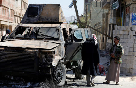 People look at an armored personnel carrier damaged during recent clashes between Houthi fighters and forces loyal to Yemen's former president Ali Abdullah Saleh in Sanaa, Yemen December 5, 2017. REUTERS/Khaled Abdullah