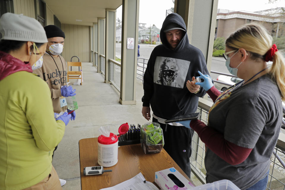 In this March 27, 2020 photo, Scott, center, picks up medication for opioid addiction at a clinic in Olympia, Wash., that is currently meeting patients outdoors and offering longer prescriptions in hopes of reducing the number of visits and the risk of infection due to the outbreak of the new coronavirus. The coronavirus pandemic is challenging the millions who struggle with drug and alcohol addiction and threatening America's progress against the opioid crisis, said Dr. Caleb Alexander of Johns Hopkins' school of public health. (AP Photo/Ted S. Warren)