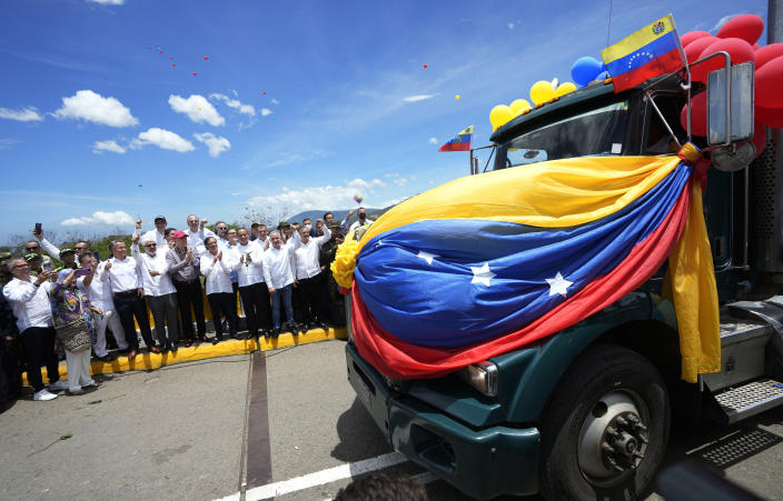A Venezuelan cargo truck adorned with Venezuelan flags and balloons crosses the Simon Bolivar International Bridge during a ceremony to mark the bridge's reopening to cargo trucks between Cucuta, Colombia and San Antonio del Tachira, Venezuela, Monday, Sept. 26, 2022, in a ceremonial act to mark the resumption of commercial relations between the two nations. Behind in the crowd are Colombia's President Gustavo Petro and Venezuela's Transportation Minister Ramon Araguayan. (AP Photo/Fernando Vergara)