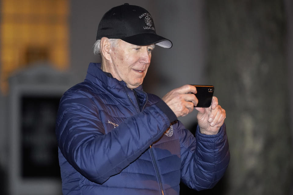 President Joe Biden uses his phone while waiting for the annual Christmas Tree Lighting ceremony to begin in Nantucket, Mass., Friday, Nov. 25, 2022. (AP Photo/Susan Walsh)