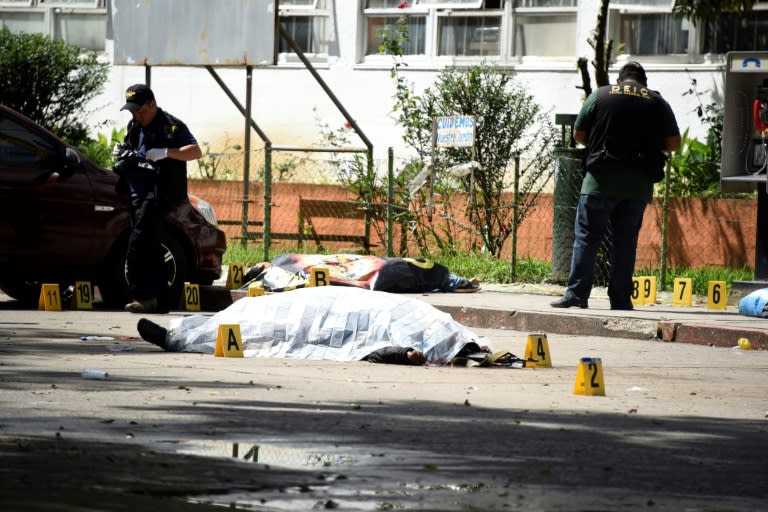 A gang shooting at a Guatemalan hospital leaves seven dead, including a prison guard (front) and a civilian caught in the crossfire, seen here covered as forensic workers examine the scene