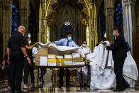 Organizers cover the boxed cremated remains of Mexicans who died from COVID-19 before a service at St. Patrick's Cathedral, Saturday, July 11, 2020, in New York. The ashes were blessed before they were repatriated to Mexico. (AP Photo/Eduardo Munoz Alvarez)