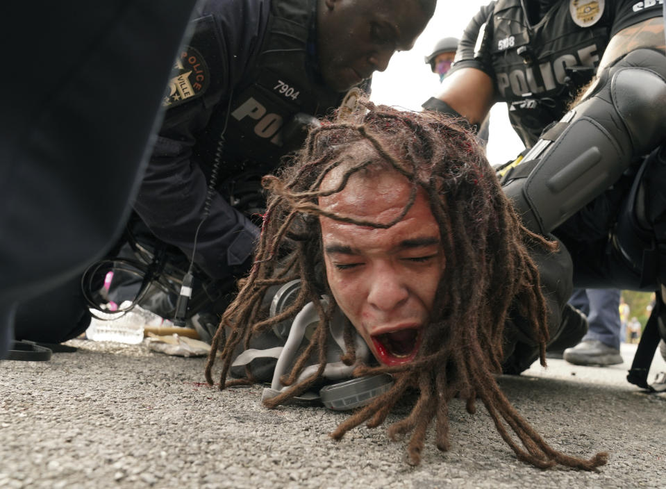 Louisville police detain a man after a group marched in protest over a lack of charges against Louisville police in Breonna Taylor's death, Wednesday, Sept. 23, 2020, in Louisville, Ky. A grand jury indicted one officer on criminal charges six months after Taylor was fatally shot by police in Kentucky. Prosecutors said two officers who fired their weapons at Taylor were justified in using force to protect themselves after they faced gunfire from her boyfriend. (AP Photo/John Minchillo)