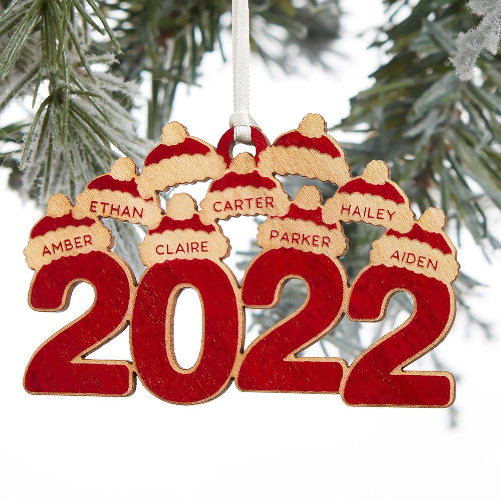 2022 Personalized Wood Ornament hanging from a tree with names on mini snow hats