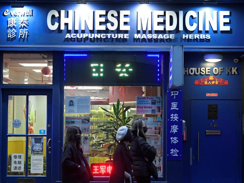 People wear masks as they walk in Chinatown district, in London