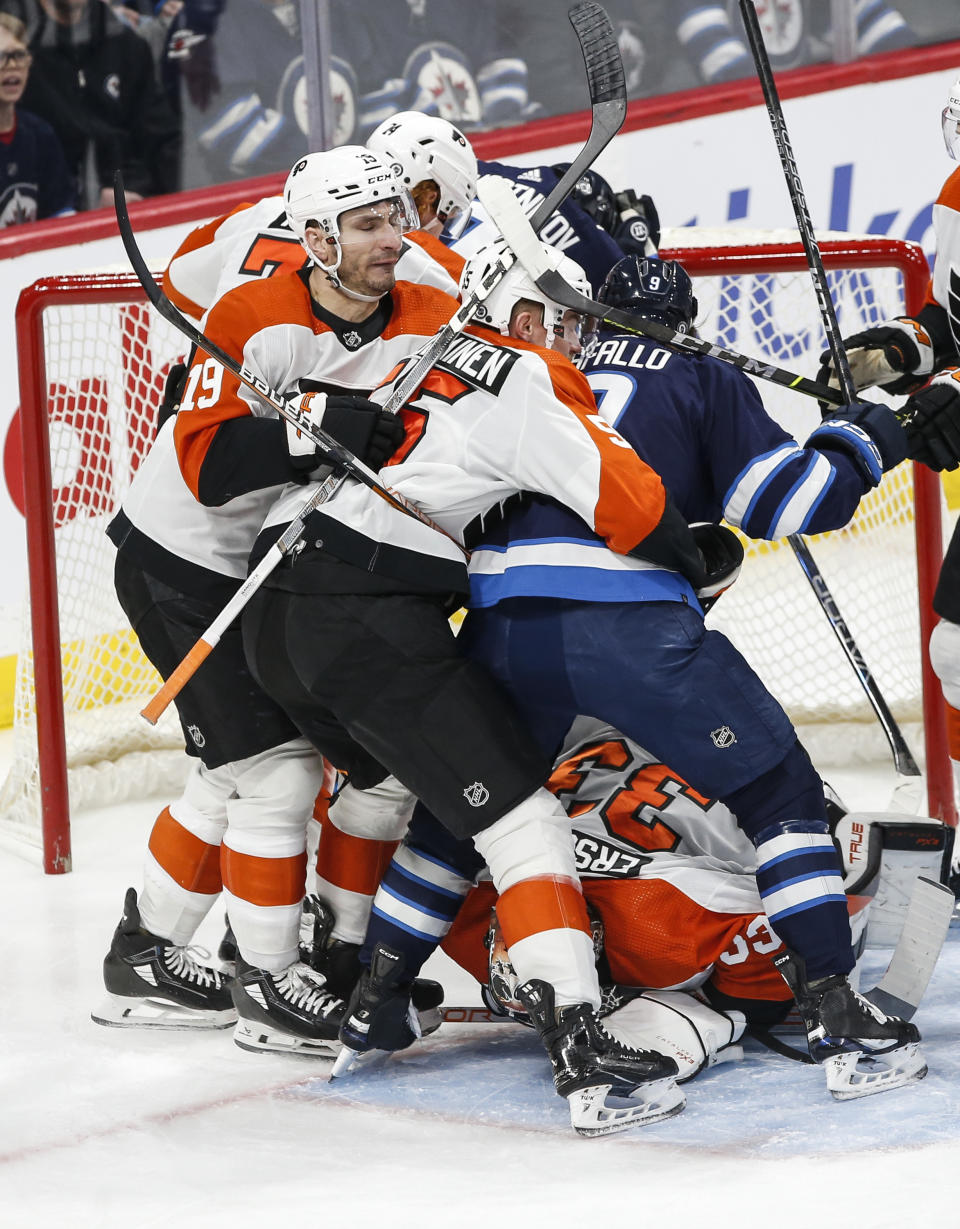 Philadelphia Flyers' Egor Zamula (5) defends against Winnipeg Jets' Alex Iafallo (9) as goaltender Samuel Ersson (33) jumps on a loose puck during the first period of an NHL hockey game in Winnipeg, Manitoba, Saturday, Jan. 13, 2024. (John Woods/The Canadian Press via AP)