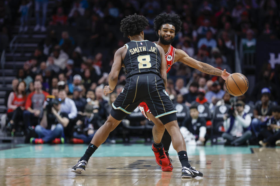 Chicago Bulls guard Coby White, right passes the ball around Charlotte Hornets guard Dennis Smith Jr. (8) during the first half of an NBA basketball game in Charlotte, N.C., Thursday, Jan. 26, 2023. (AP Photo/Nell Redmond)