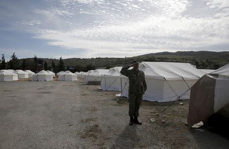 A Greek soldier salutes as he stands next to tents at a newly operational relocation camp for refugees in Schisto, near Athens, Greece, February 16, 2016. REUTERS/Alkis Konstantinidis