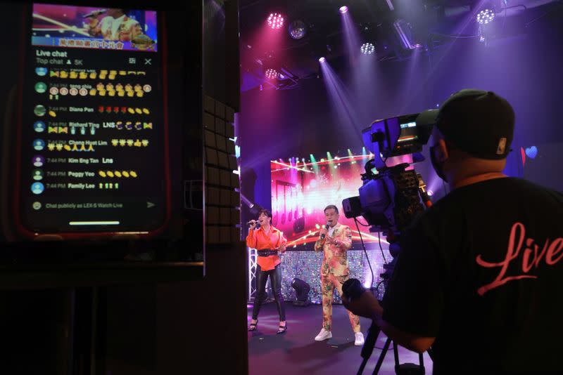 Live comments from viewers are displayed on a screen as getai Singapore Febe Huang and Leon Lim perform at a live streaming getai show at a studio in Singapore