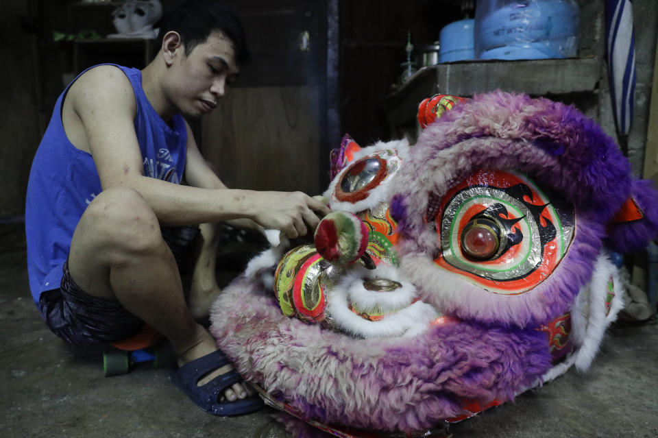 A member of a Dragon and Lion dance repair a lion's head as the group seeks other ways to earn a living at a creekside slum in Manila's Chinatown, Binondo, Philippines on Feb. 3, 2021. The Dragon and Lion dancers won't be performing this year after the Manila city government banned the dragon dance, street parties, stage shows or any other similar activities during celebrations for Chinese New Year due to COVID-19 restrictions leaving several businesses without income as the country grapples to start vaccination this month. (AP Photo/Aaron Favila)