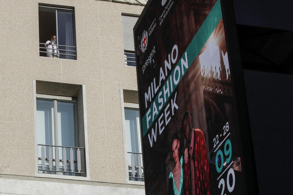 Un hombre mira por una ventana mientras una pantalla anuncia la Semana de la Moda de Milán en Milán Italia el miércoles 23 de septiembre de 2020. (Foto AP/Luca Bruno)