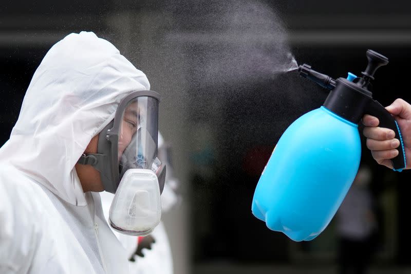 A volunteer from the Blue Sky Rescue team wearing a protective suit gets disinfected at the Qintai Grand Theatre in Wuhan