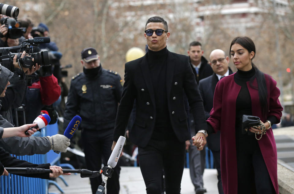 El futbolista portugués Cristiano Ronaldo llega al tribunal en Madrid junto a su novia Georgina Rodríguez, el martes 22 de enero de 2019. Cristiano se declaró culpable de fraude fiscal en España y recibió una condena suspendida de dos años de prisión y multas de 21,6 millones de dólares. (AP Foto/Manu Fernández)