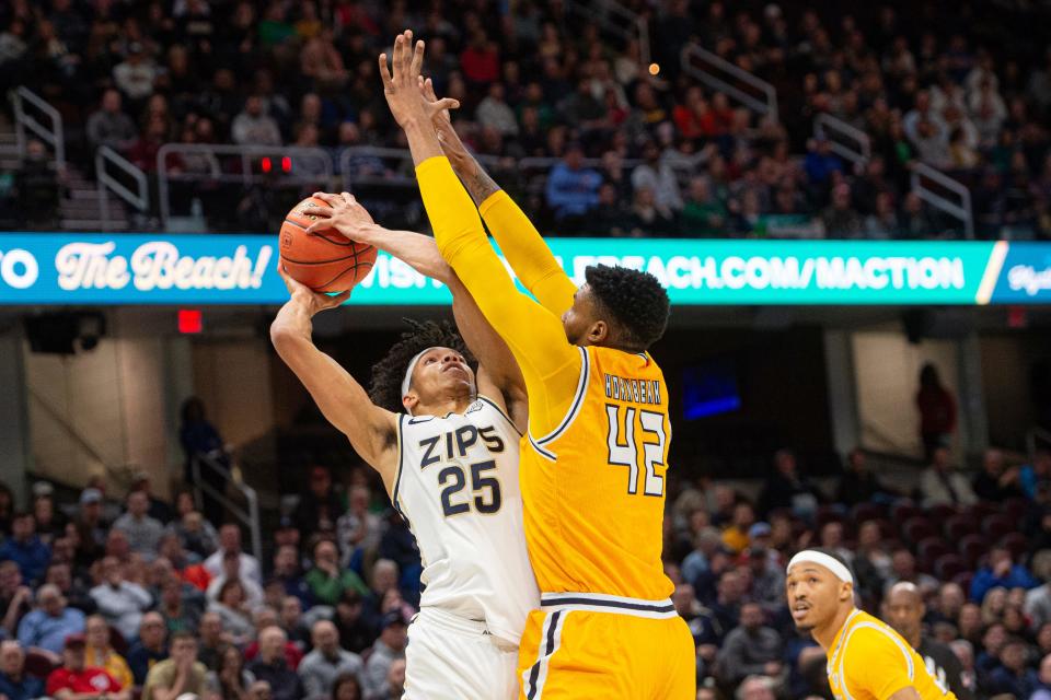Akron's Enrique Freeman (25) attempts to shoot over Kent State's Cli'Ron Hornbeak during the first half of the Mid-American Conference Tournament championship game, Saturday, March 16, 2024, in Cleveland.