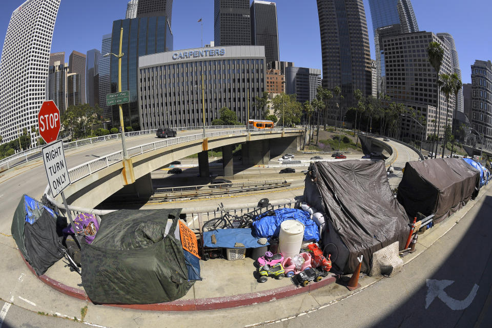 FILE - This May 21, 2020 file photo shows a homeless encampment at the corner of Wilshire Boulevard and Beaudry Avenue along the 110 Freeway during the coronavirus outbreak. in downtown Los Angeles. A judge has approved an agreement in which the city and county of Los Angeles will provide housing for almost 7,000 homeless people who live near freeways. Officials said Thursday, June 18, 2020 the city will provide 6,000 new beds within 10 months and another 700 beds over 18 months. Meanwhile the county will spend $300 million over five years to fund services for the people. (AP Photo/Mark J. Terrill, File)