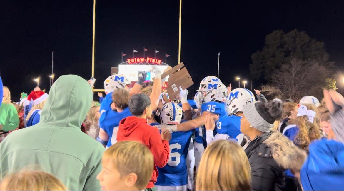 Memorial players and students celebrate with the sectional trophy after beating Reitz 21-16 at Enlow Field.